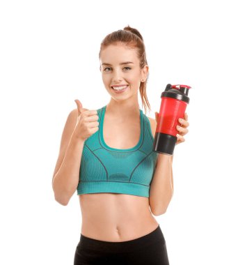 Protein içeceği olan genç bir kadın beyaz arka planda baş parmağını gösteriyor.