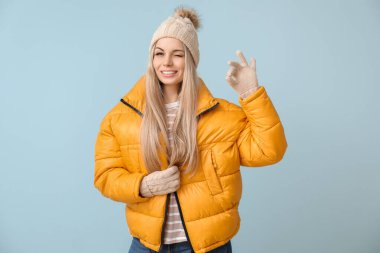 Kışlık giysiler içinde güzel bir kadın. Renkli arka planda güzel bir jest yapıyor.