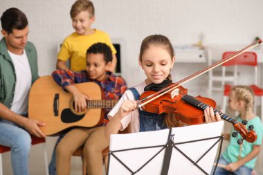 Müzik okulunda keman çalan tatlı küçük kız.