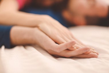 Yatakta uyuyan genç bir çiftin elleri