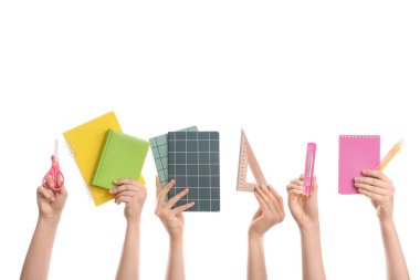 Beyaz arka planda okul malzemesi olan bir sürü el.