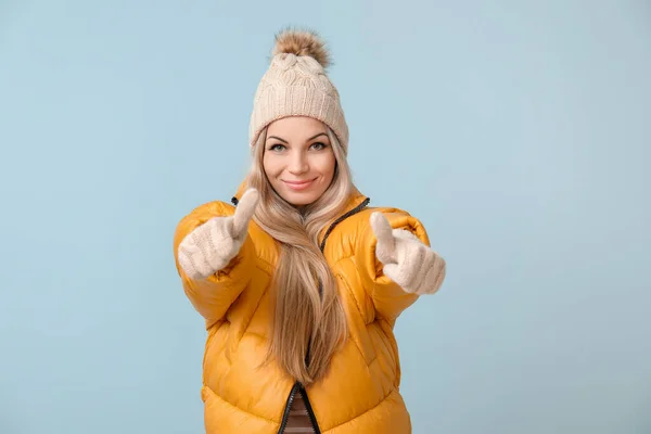 穿着冬衣的年轻貌美的女人在色彩背景上表现出大拇指向上的姿势 — 图库照片