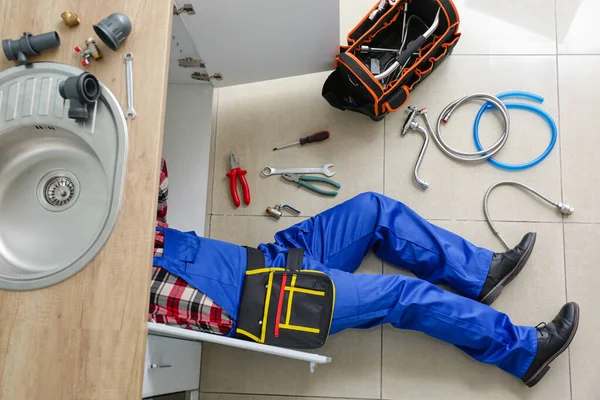 Plumber repairing sink in kitchen