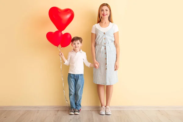 幸せな男の子と彼の母親と風船の近くの色の壁 — ストック写真