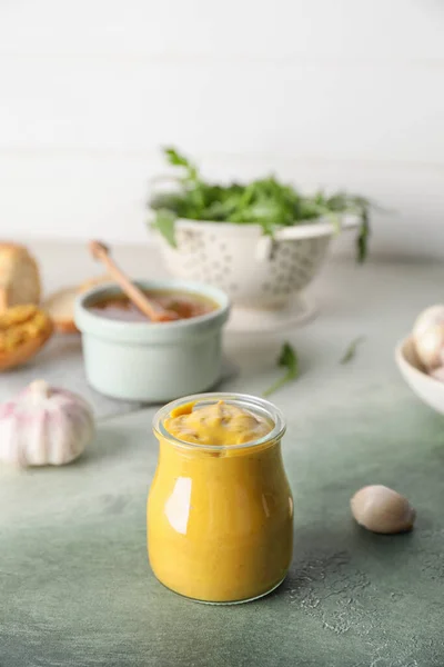 Jar of tasty honey mustard sauce on color background