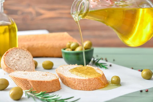 Pouring of tasty olive oil from bottle on fresh bread