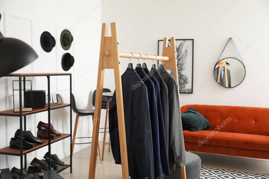 Rack with stylish male clothes in dressing room