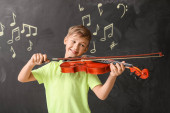 Malý chlapec hraje na housle v hudební škole
