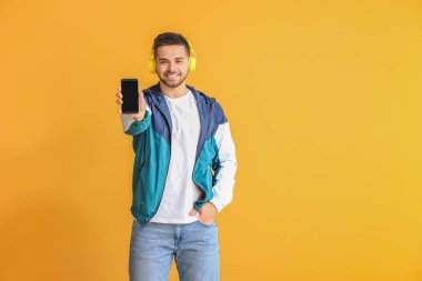 Arka planda cep telefonu ve kulaklığı olan genç adam.