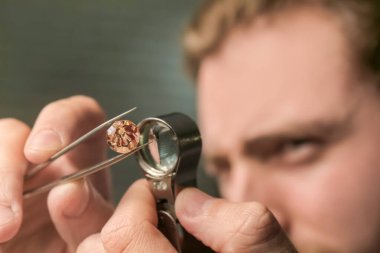 Jeweler examining gemstone in workshop, closeup clipart