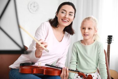 Özel müzik öğretmeni evde küçük bir kıza keman dersi veriyor.