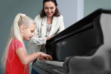 Özel müzik öğretmeni küçük kıza piyano dersleri veriyor.