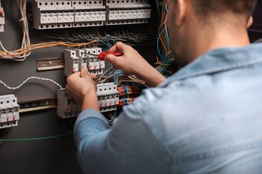 Erkek elektrikçi dağıtım tahtasını tamir ediyor.