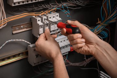 Erkek elektrikçi dağıtım panelini tamir ediyor, yakın plan.