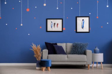 Mavi duvarın yanında kanepesi olan şık bir oda.