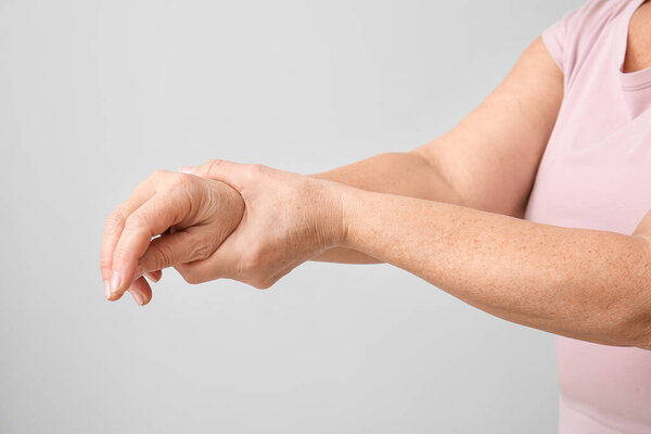 Senior woman suffering from Parkinson syndrome on grey background