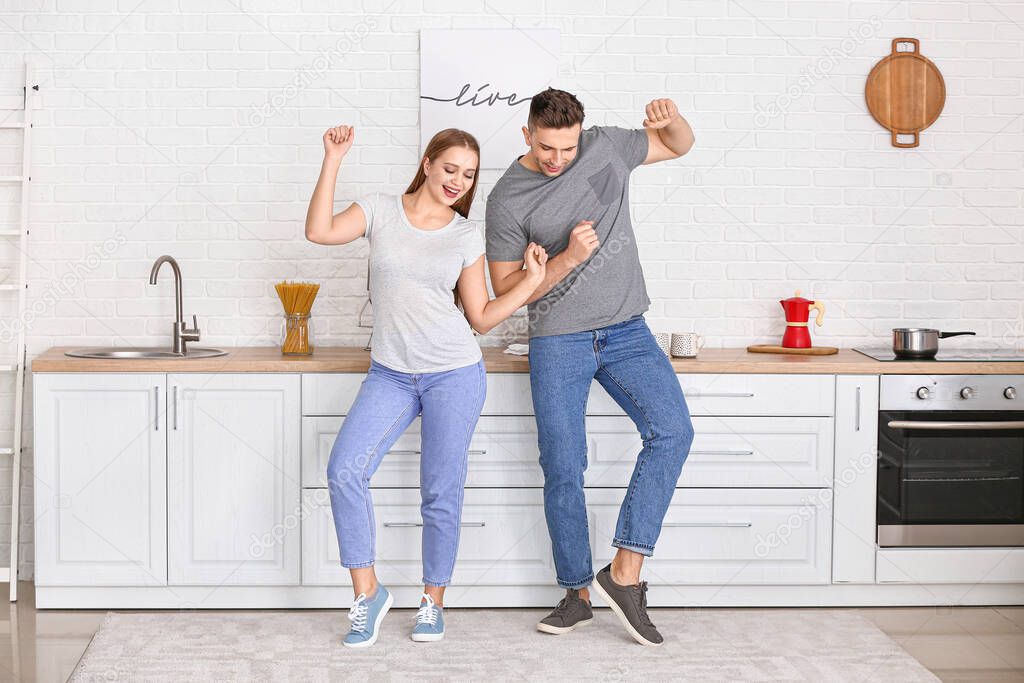 Happy young couple dancing in kitchen