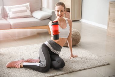 Evde protein içeceği olan genç bir kadın.