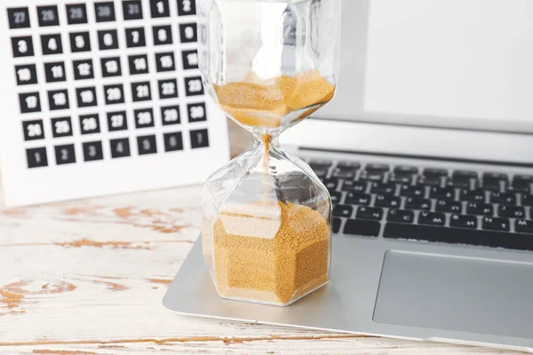 Laptop, calendar and hourglass on table. Deadline concept