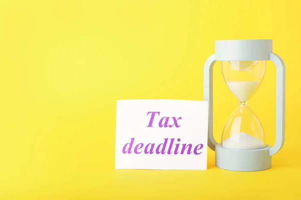 Hourglass and paper with text TAX TIME on color background