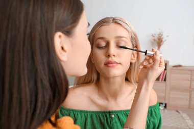 Güzel genç kadınlar evde birlikte makyaj yapıyorlar.