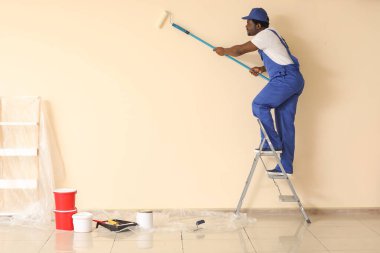Afro-Amerikalı ressam odada tamirat yapıyor.