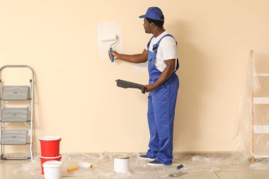 Afro-Amerikalı ressam odada tamirat yapıyor.