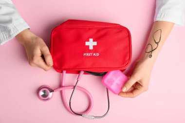 Steteskop ve renk arkaplan üzerine ilk yardım çantası olan doktorun elleri
