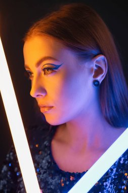 Koyu arkaplanda neon lambaları olan güzel bir kadının tonlu portresi.