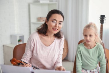 Özel müzik öğretmeni evde küçük bir kıza keman dersi veriyor.