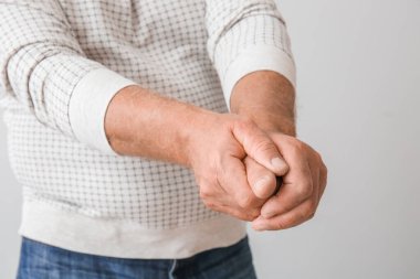 Gri arka planda Parkinson sendromu olan yaşlı adam, yakın plan.
