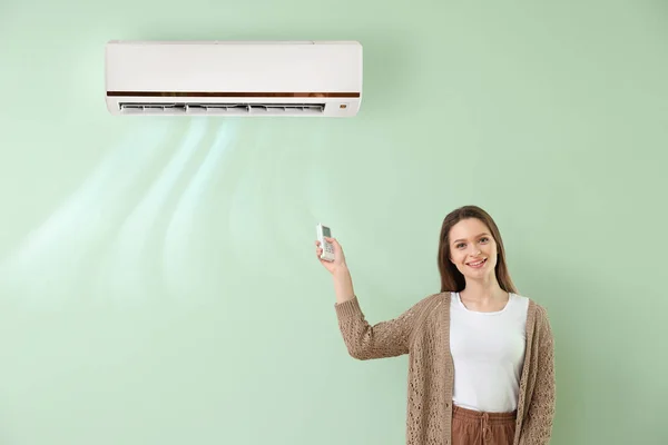 Young Woman Switching Air Conditioner Color Wall — Stock Photo, Image