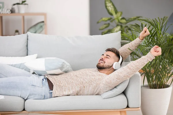 Unge Man Lyssnar Musik När Han Ligger Soffan Hemma — Stockfoto