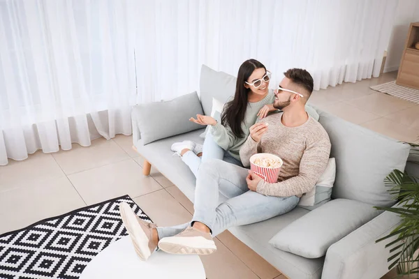 Young couple watching movie while sitting on sofa at home