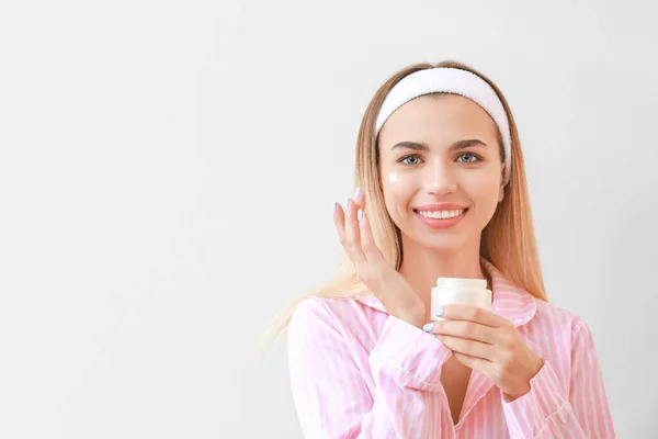 Hermosa Joven Que Aplica Crema Cara Contra Fondo Claro — Foto de Stock