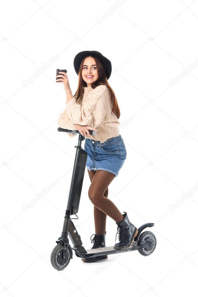 Young woman with kick scooter and cup of coffee on white background