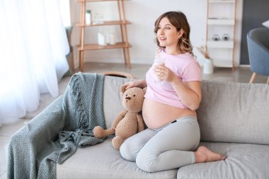 Güzel hamile kadın evde yoğurt içiyor.