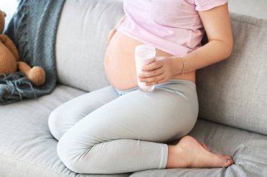 Güzel hamile kadın evde yoğurt içiyor.