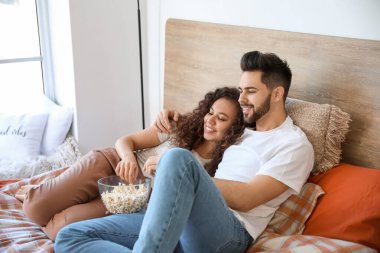 Mutlu genç çift yatak odasında film izliyor.