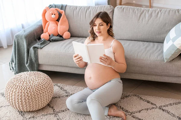 Красивая Беременная Женщина Читает Книгу Дома — стоковое фото