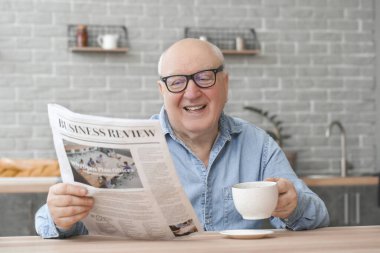 Evde gazete okurken çay içen yaşlı bir adamın portresi