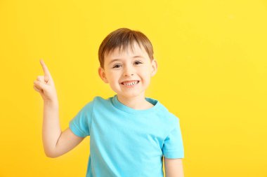 Mutlu gülümseyen küçük çocuk arka plandaki bir şeyi işaret ediyor.