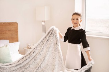 Küçük sevimli oda hizmetçisi otelde yatak yapıyor.