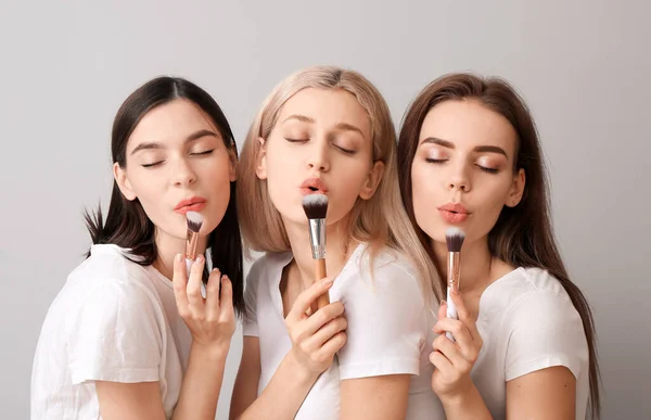 Hermosas Mujeres Jóvenes Aplicando Maquillaje Sobre Fondo Claro — Foto de Stock