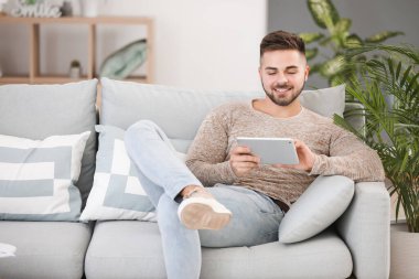 tablet bilgisayar evde kanepede oturan genç adam