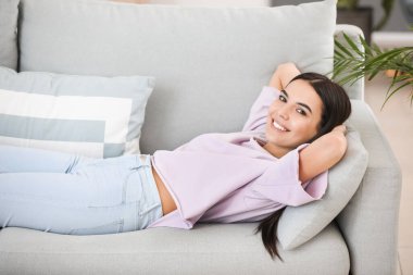 evde bir kanepede oturan genç bir kadın