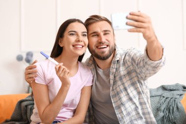Hamilelik testi olan mutlu genç çift evde selfie çekiyor.