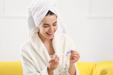 mutlu genç kadın evde gebelik testi ile