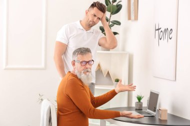 Genç adam babasına modern bilgisayarla başa çıkmayı öğretiyor.