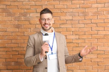 Tuğla arka planda mikrofonu olan erkek gazeteci